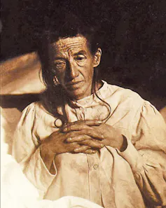 A black and white image of a woman looking down, with her fingers intertwined.