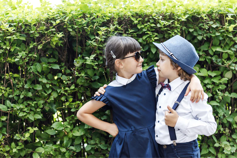 A young girl and boy have their arms around each other.