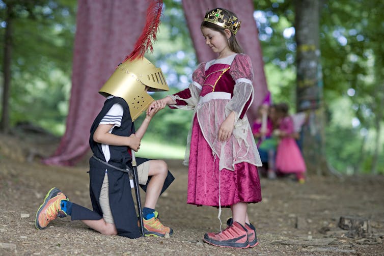 A child dressed as a knight takes the hand of a child dressed as a princess.