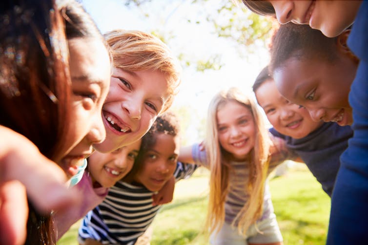 A group of children put their arms around each other, smiling.