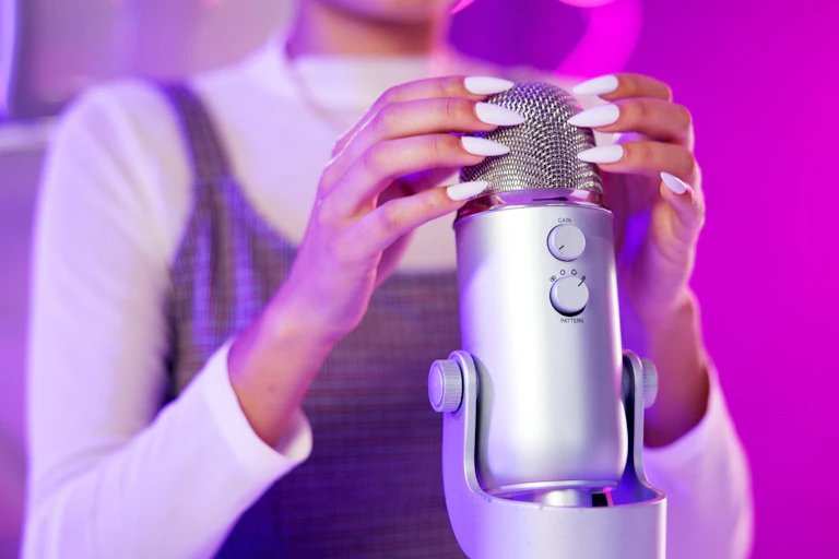 Close up of woman with long nails touching a microphone.