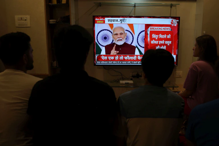 People watch as Modi speaks on a TV screen.