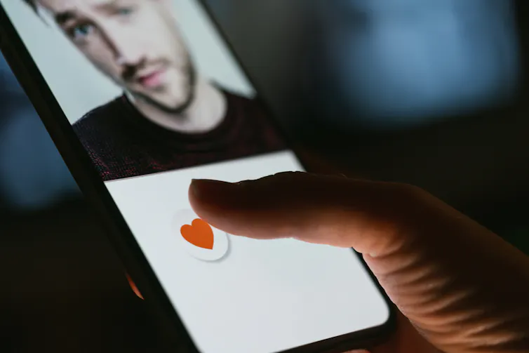 A person hitting the heart icon on a dating profile on their phone.