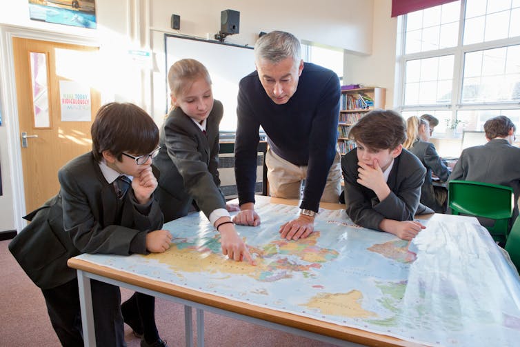 Teacher and pupils looking at world map