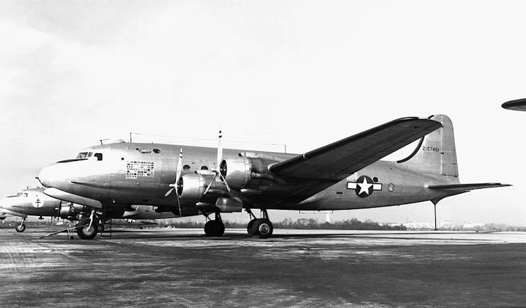 Black-and-white photo of a plane parked on a runway.