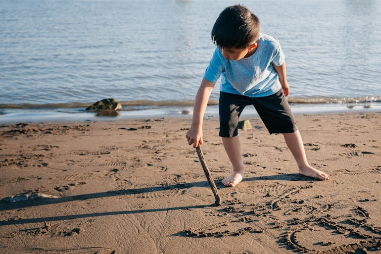 A child writing in the sand.