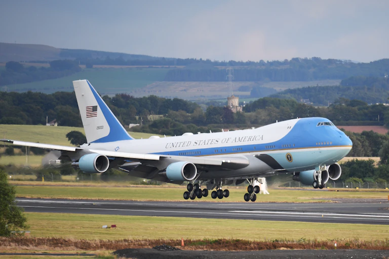 Blue and white plane lands on runway.
