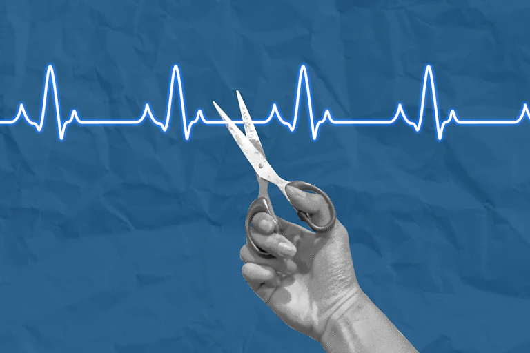 Hand with scissors cutting an ECG graph line.