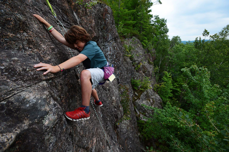 A young person seen climbing a rock.
