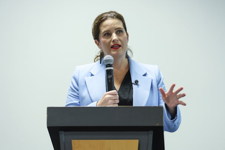 Nicola Willis speaks behind a podium.