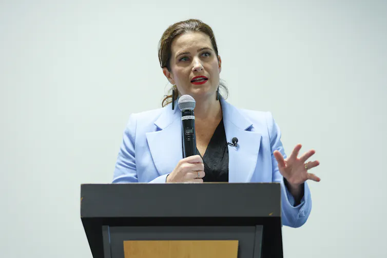 Nicola Willis speaks behind a podium.