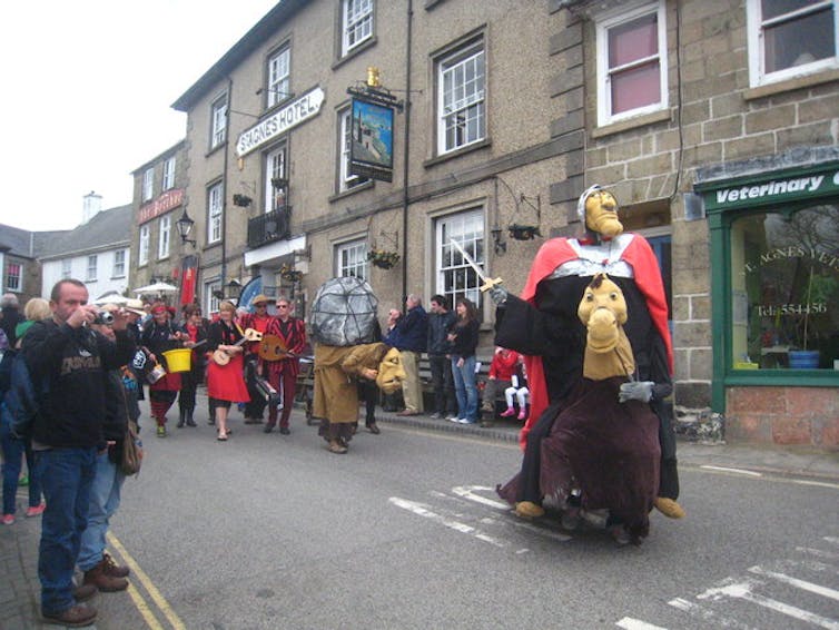 a pageant led by someone in a giant costume on a street
