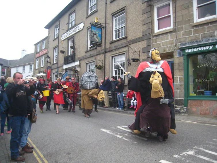 a pageant led by someone in a giant costume on a street