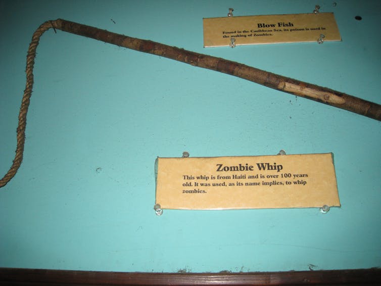 a whip in a glass case, with historical note