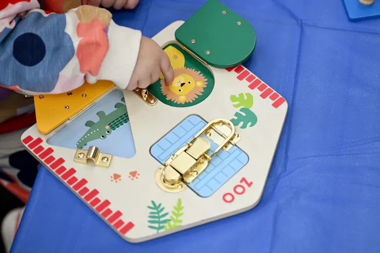 A young child plays with a wooden toy.