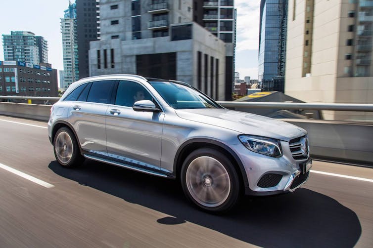 A silver SUV driving on a city road.