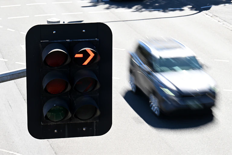 A blurred SUV driving past a red arrow on a traffic light.