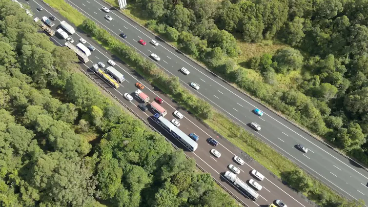 A traffic jam on highway surrounded by bush.