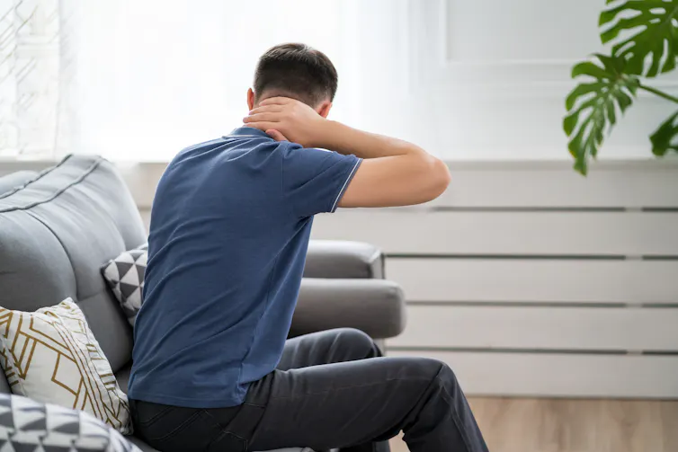 A man clutches his neck in pain.