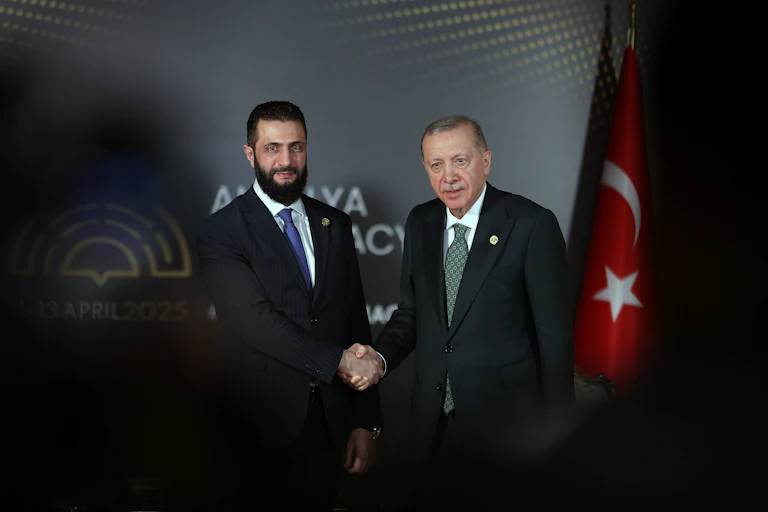 Two men in suits shake hands for a photo.