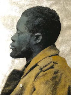 A colourised portrait in profile of an unsmiling African man with a beard in a thick brown coat.