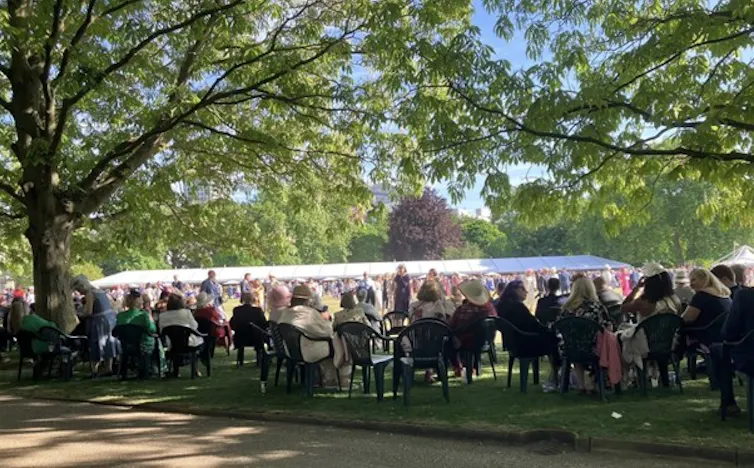 People seen in the shade in chairs and in a tent.