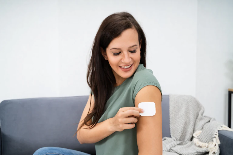 Woman applying patch on her arm at home