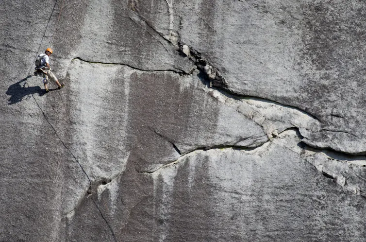 A person seen suspended from a rock face.