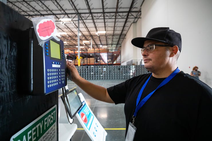 A person swipes a card in a machine on a wall.
