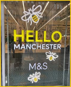 A shop window that reads Hello Manchester M&S and has images of bees