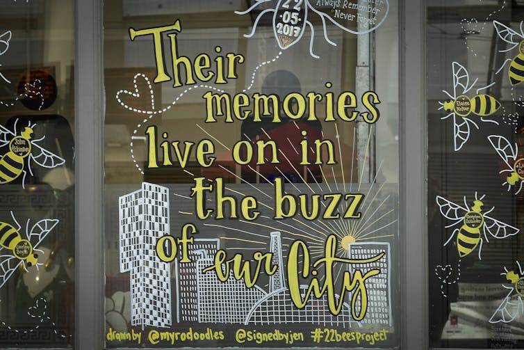 Window decoration with images of bees reads 'their memories live on in the buzz of the city'