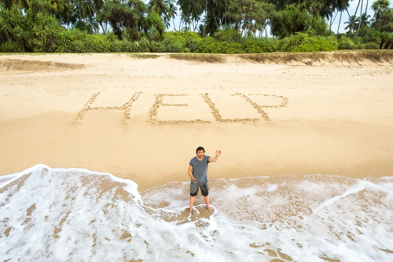Man stuck on uninhabited island, inscription in sand says Help