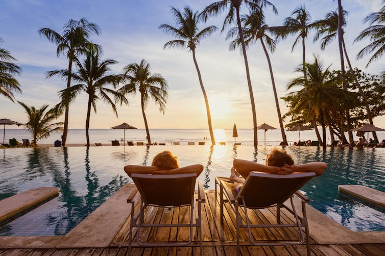 couple relaxing on tropical beach at sunset in hotel