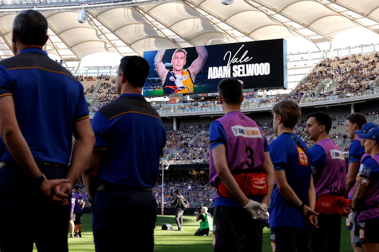 West Coast staff line up during a tribute to former Eagles player Adam Selwood at Optus Stadium, Perth.