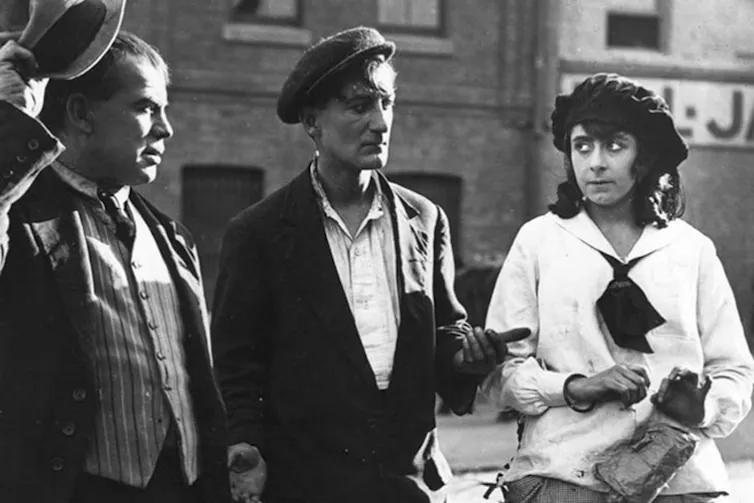 A black and white photo of two men and a woman on a film set.