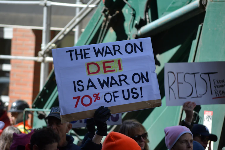 Manifestants aux États-Unis brandissant une pancarte pour le défense des DEI.