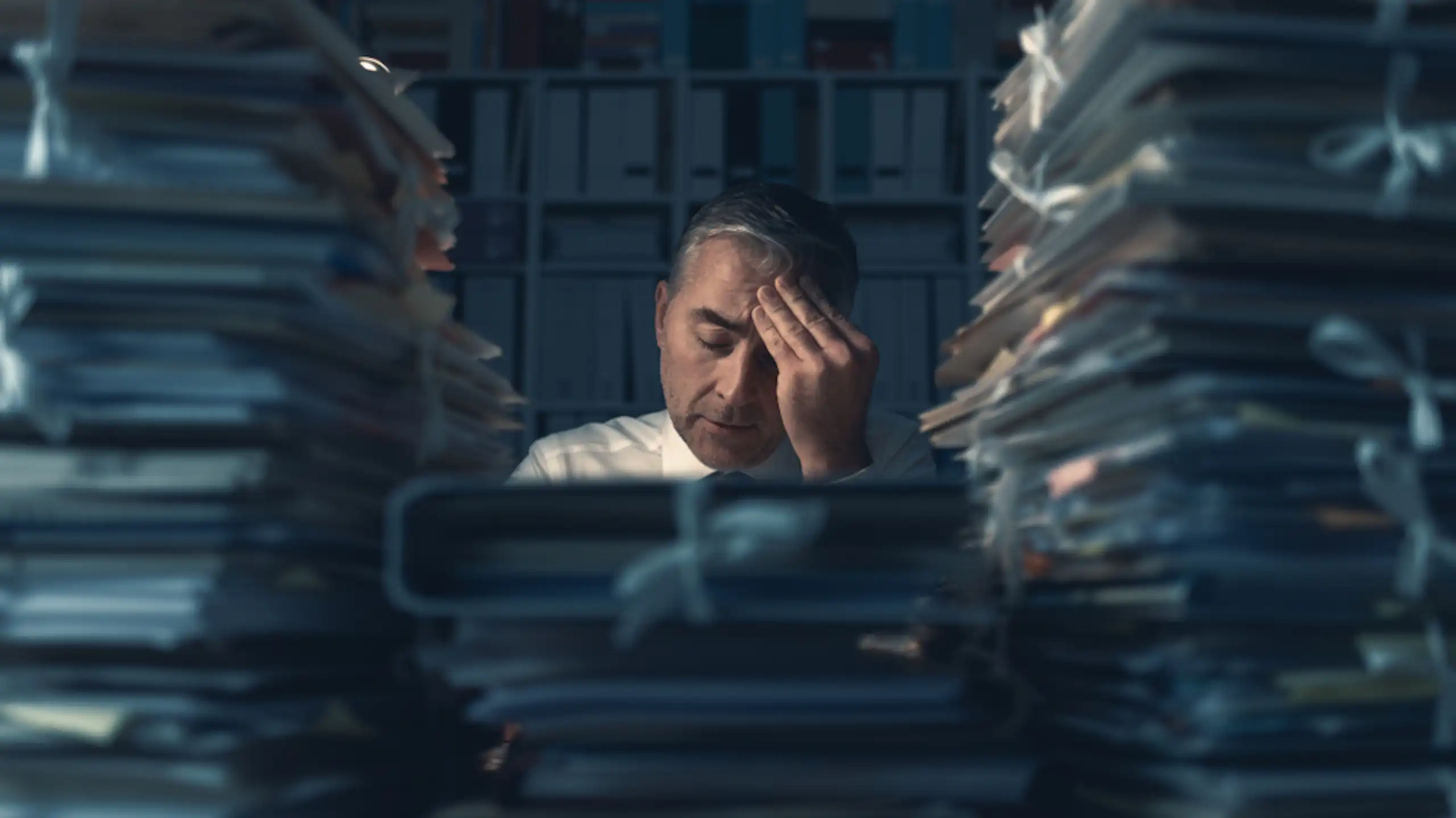 Un homme débordé assis face à son bureau