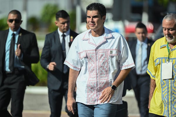 A man in short sleeves walks with a group behind him.