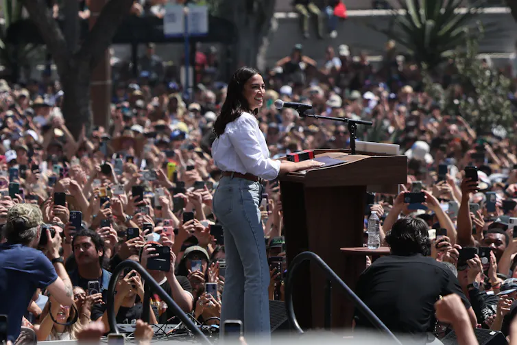 Alexandria Ocasio-Cortez delivers a speech on stage.