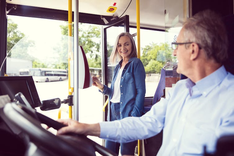 Woman taps her bus pass and smiles at the driver