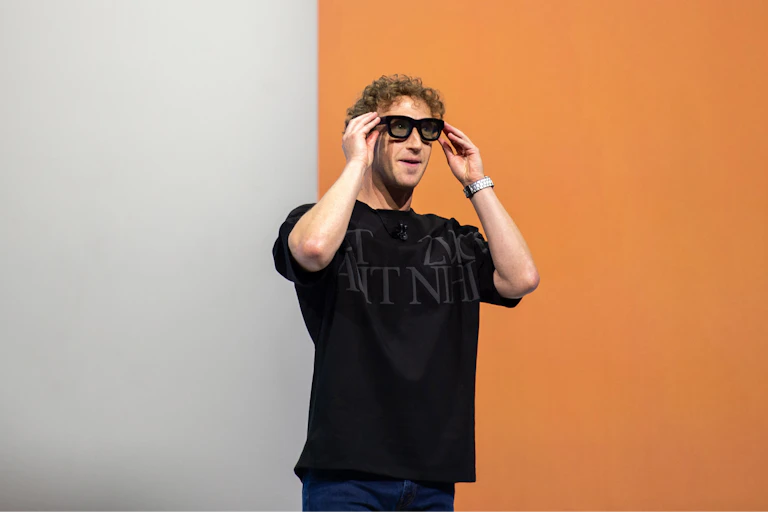 Young man wearing baggy black t-shirt puts on a pair of sunglasses.