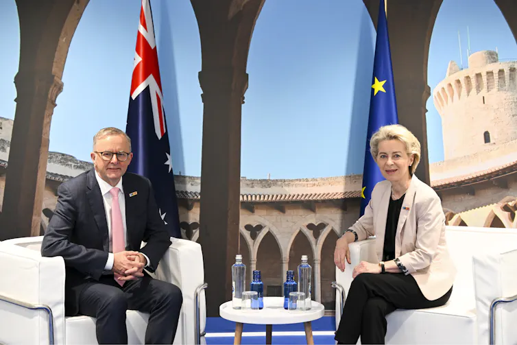 Prime Minister Anthony Albanese and European Commission President Ursula von der Leyen seated on white chairs in front of flags