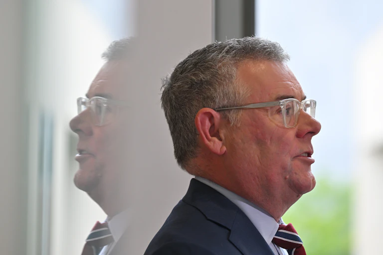 Side profile of Murray Watt with his reflection facing in the other direction