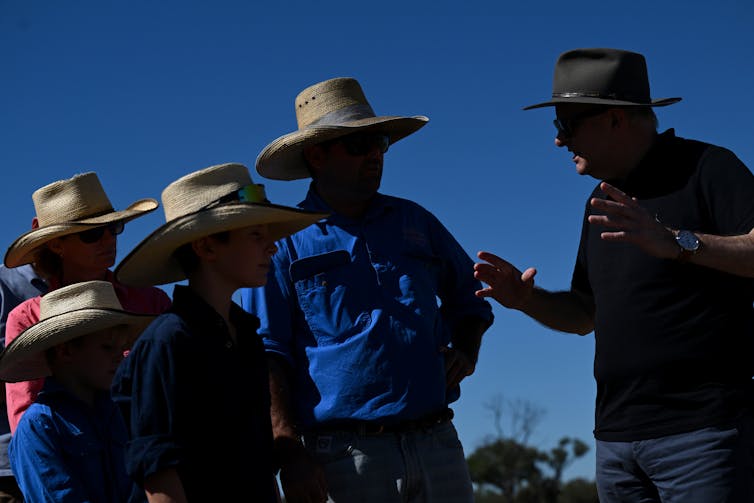 five people in broad-brimmed hats in silhouette
