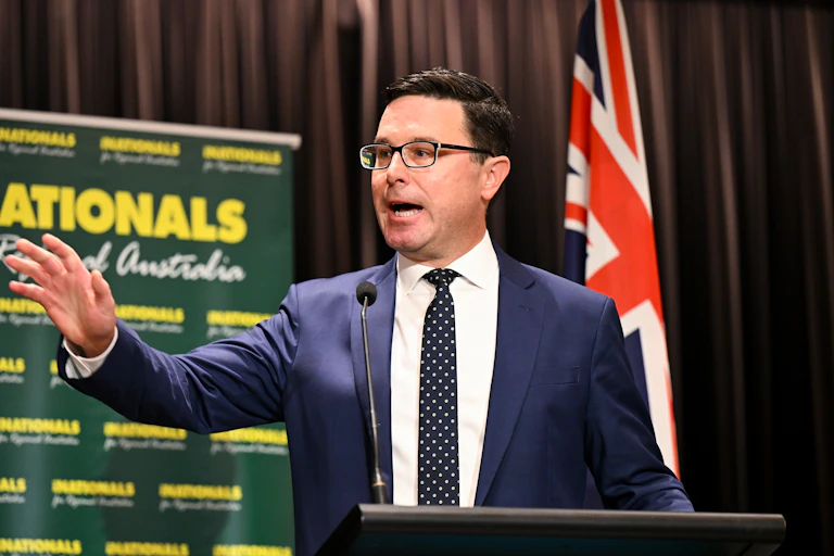 David Littleproud stands in front of a Nationals sign and an Australian flag