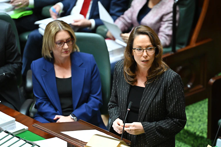 Two women, one seated, one standing behind a table