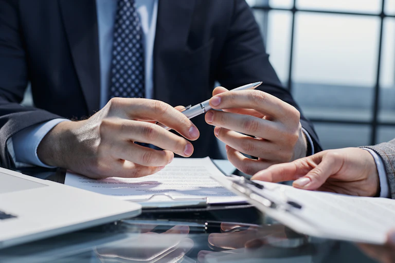 un homme en costume (on ne voit pas sa tête) sur le point de signer un contrat