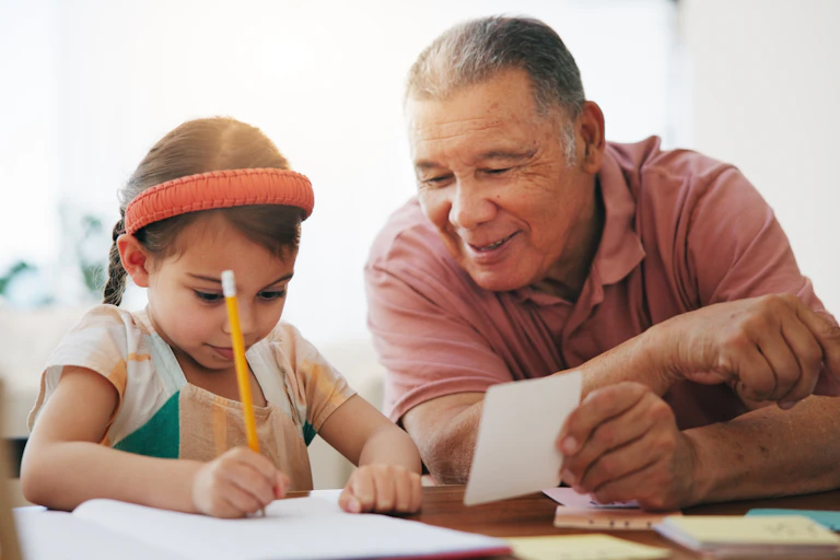 Un anciano ayuda a una niña en sus tareas escolares