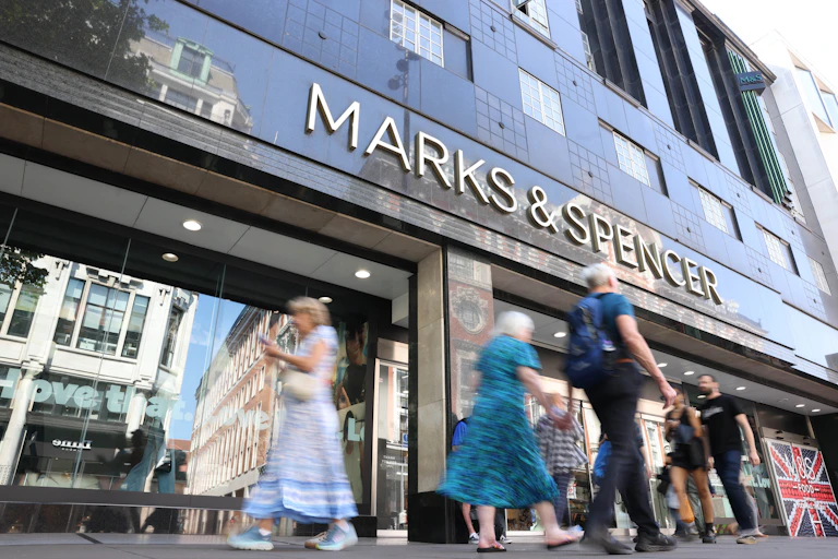 shoppers pass by the front of a large marks and spencer store