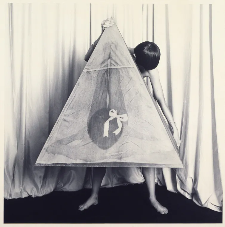 Chadwick holding a large photo of herself posed in a shape that looks like a vulva